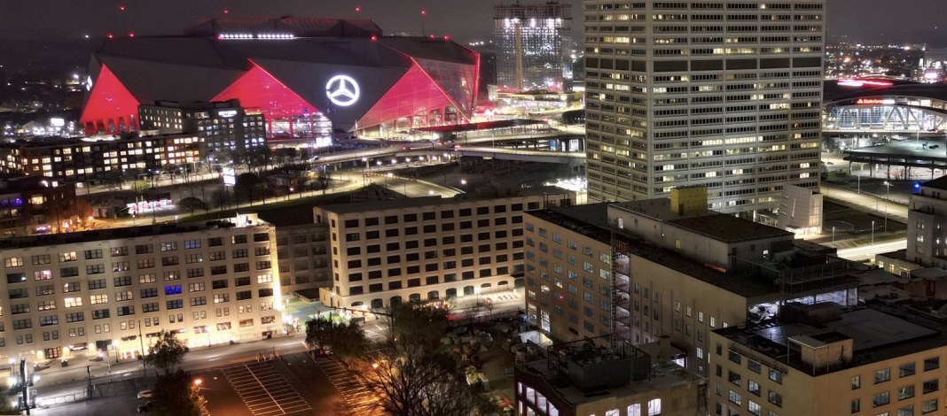 Aerial night view of South Downtown Atlanta buildings with Mercedes-Benz Stadium lit red in the background