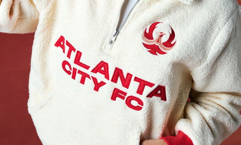 A cream fleece pullover with Atlanta City FC embroidered in red and a red phoenix crest on the chest