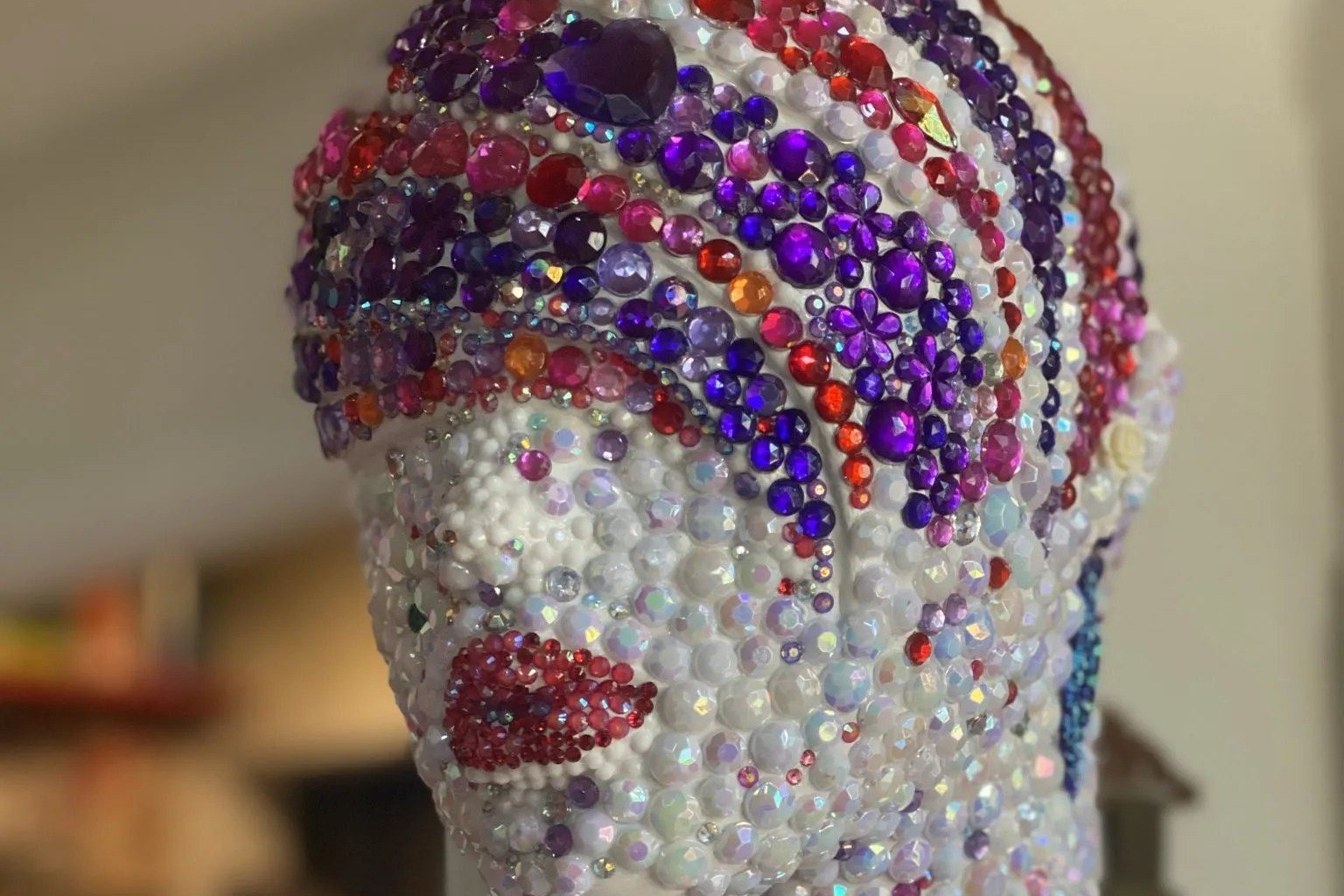 Detail of a mannequin sculpture covered in colorful beads and gemstones by Diana Ries Sheldon.