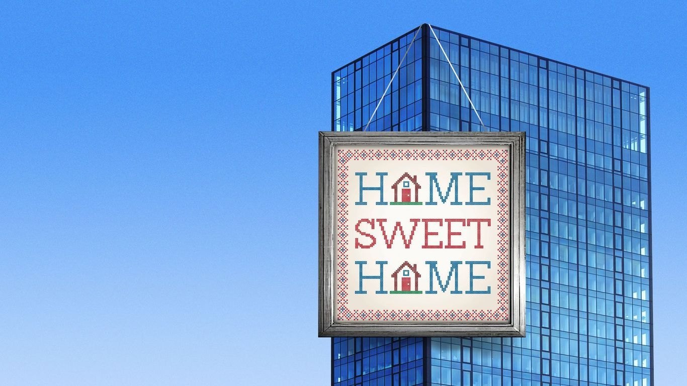 Glass office tower against a blue sky with a framed Home Sweet Home cross-stitch sign hanging from its top