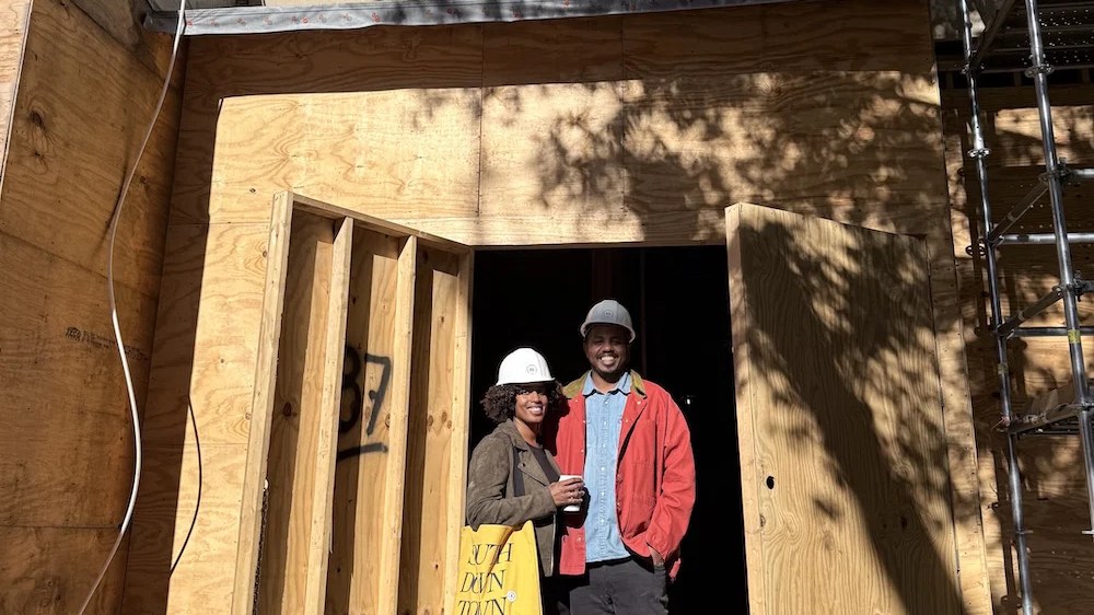Shyretha and Michael Sheats in hard hats at the doorway of 87 Broad Street during Mule Train construction
