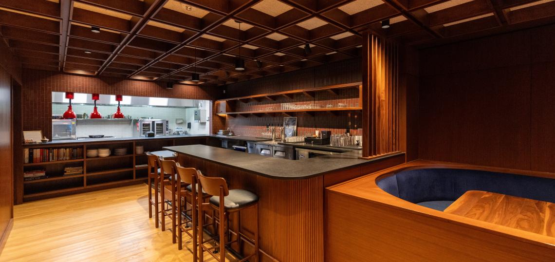 Interior of Mule Train, the new farm-to-table restaurant at 87 Broad St. in South Downtown, with walnut walls, an open kitchen and a blue banquette