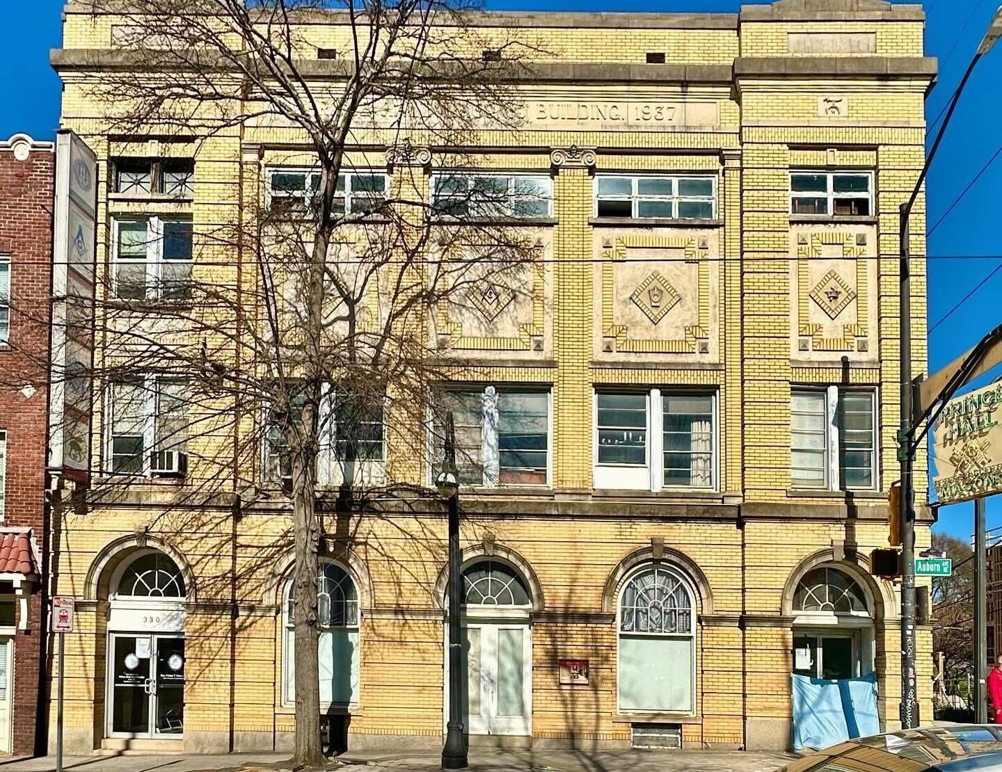Yellow-brick facade of the three-story 1937 Prince Hall Masonic building on Auburn Avenue, with arched ground-floor windows and a Prince Hall Masons sign at the corner
