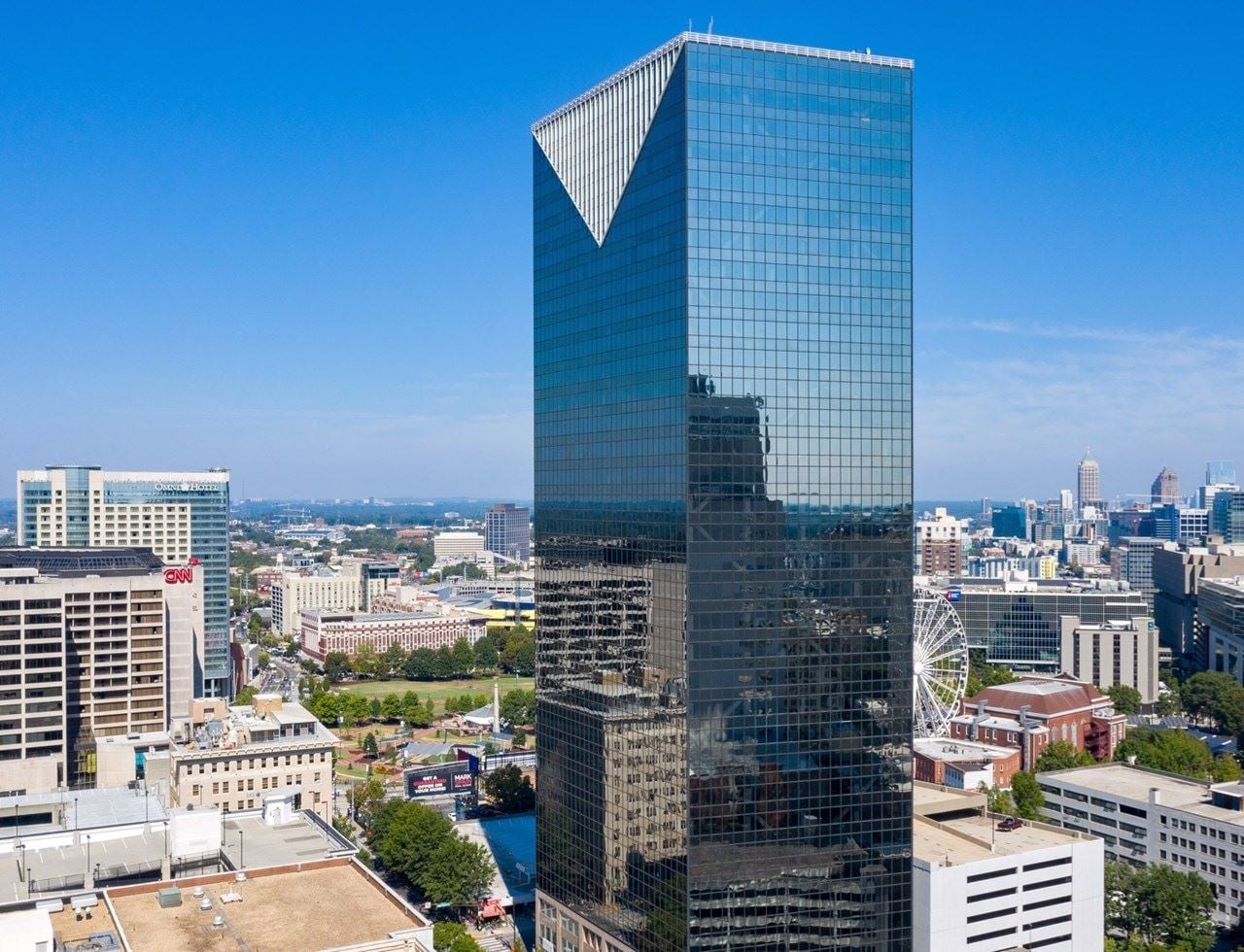 Aerial view of the 36-story 101 Marietta Street tower with its chevron roof beside Centennial Olympic Park