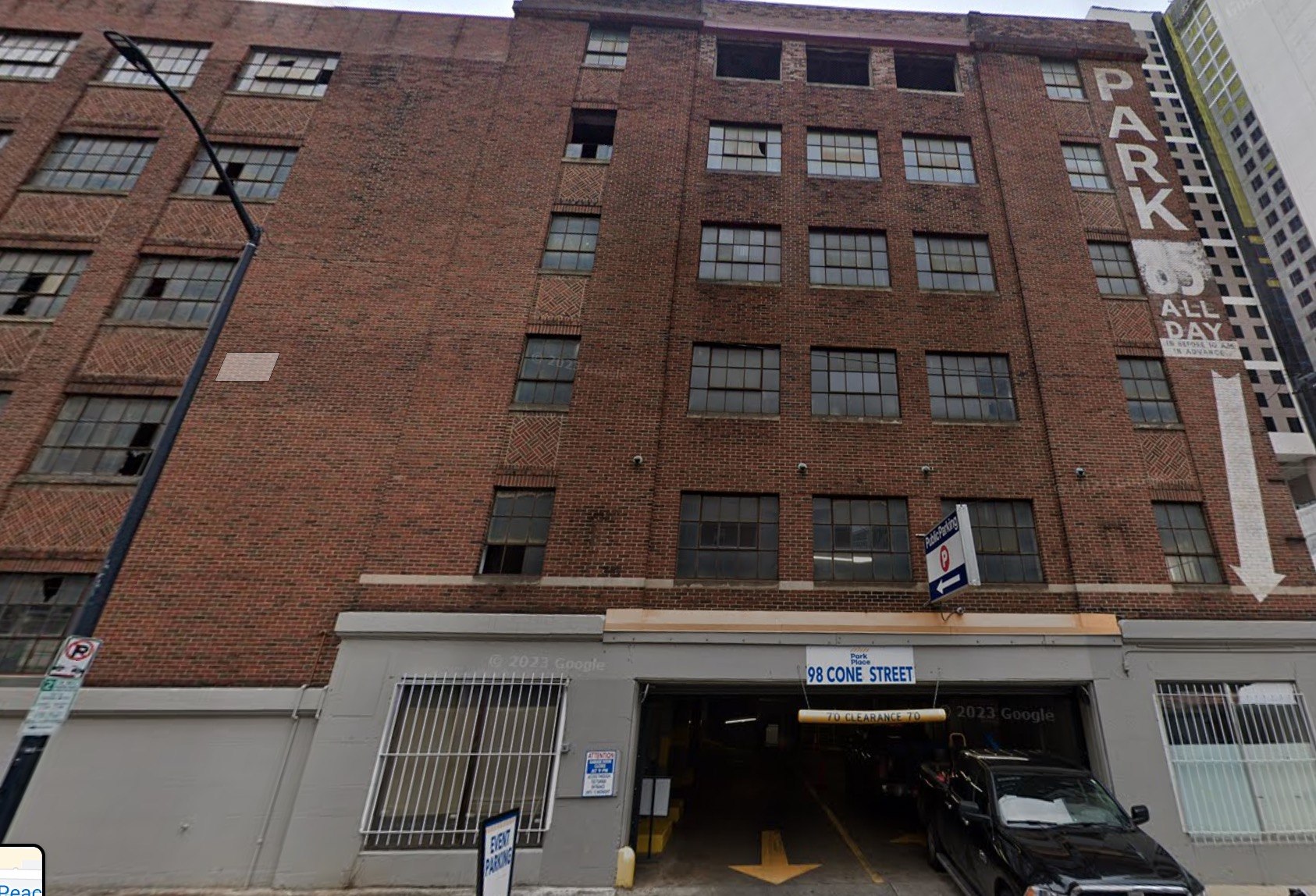 The six-story brick parking garage at 98 Cone Street in downtown Atlanta, with a painted Park sign on its corner and a newer high-rise rising behind it