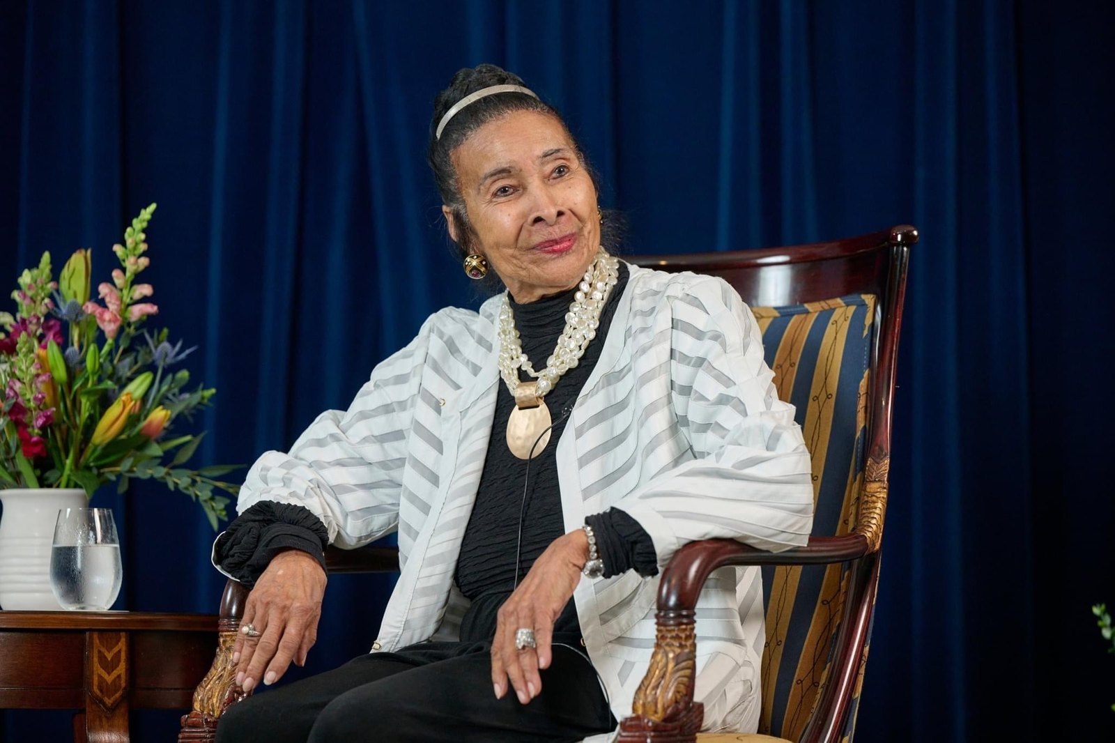 Xernona Clayton seated in an armchair on stage in front of a blue curtain during the Sweet Auburn Stories conversation