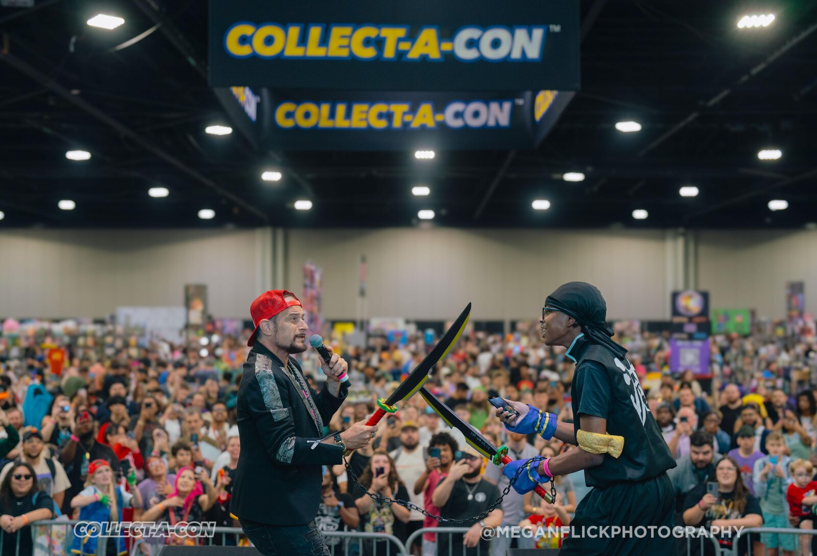 Two costumed performers face off with foam weapons on the Collect-A-Con main stage beneath illuminated COLLECT-A-CON banners before a packed crowd at the Georgia World Congress Center