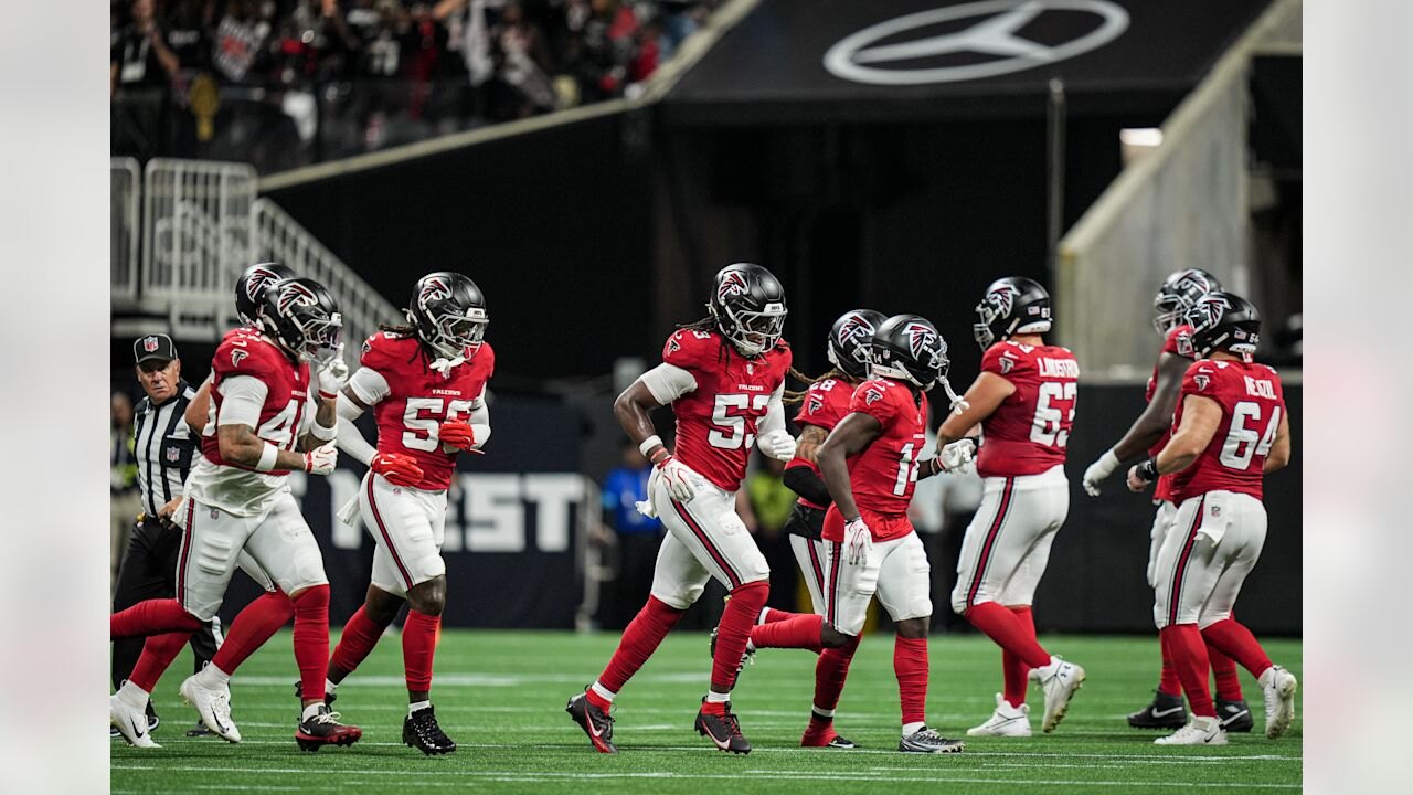 Atlanta Falcons players in red home uniforms take the field at Mercedes-Benz Stadium beneath the Mercedes-Benz star, ahead of the Falcons home game against the San Francisco 49ers.