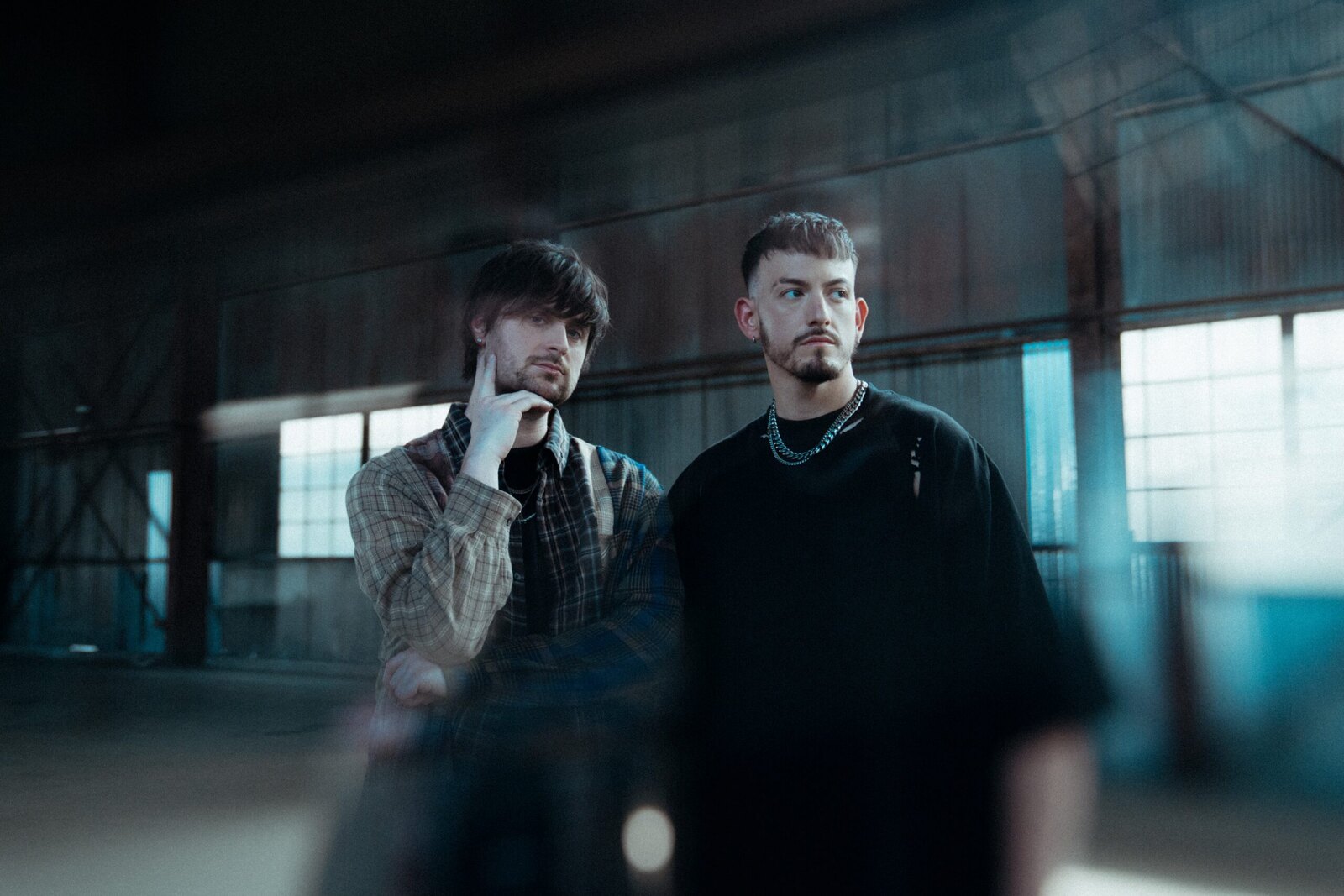 Nevertel band promo photo - two members standing in a dim industrial warehouse - key art for their October 18, 2026 show with Rivals and Ocean Sleeper at Hell at The Masquerade in Atlanta