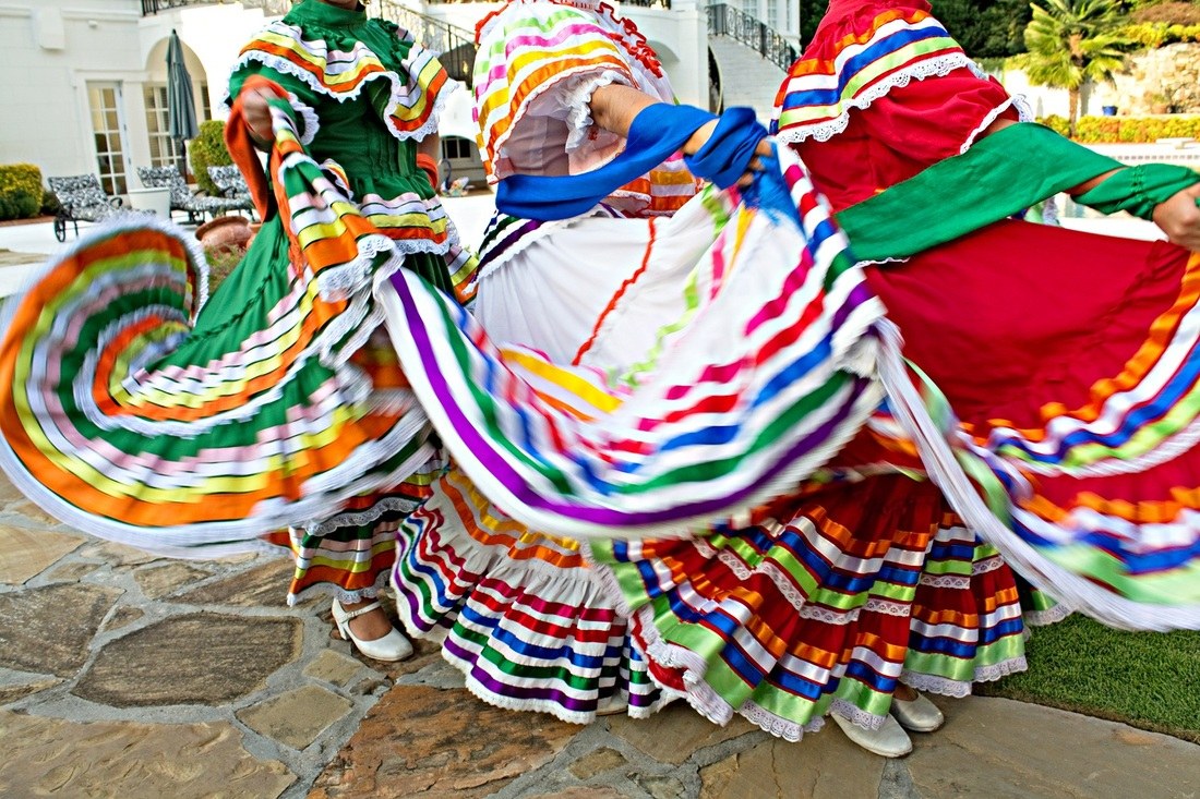 Dancers from Alma Mexicana Danza Folklorica swirl brightly striped folklorico skirts in green, red, blue and white during an outdoor performance