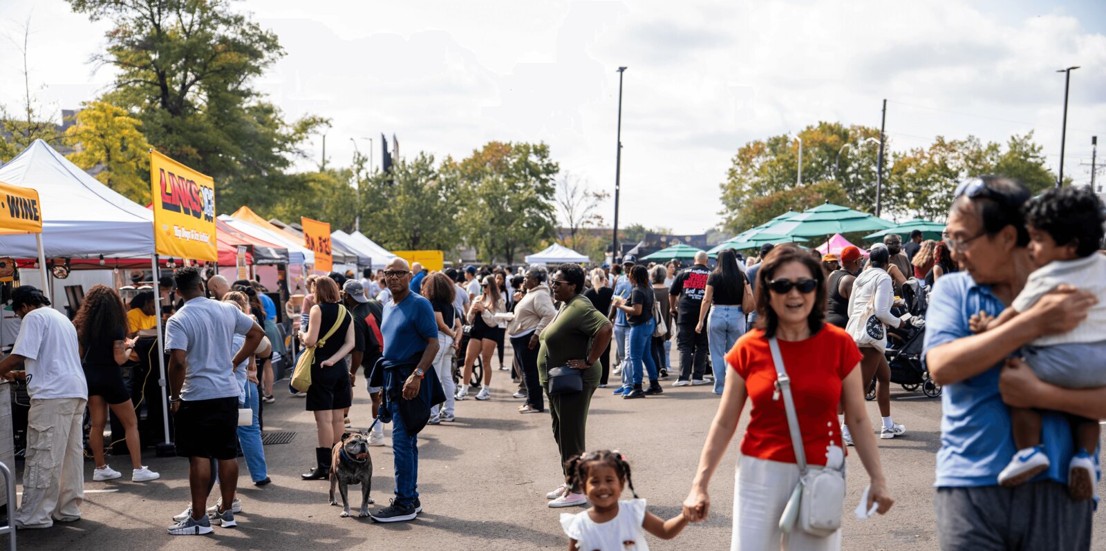 Crowds browsing tented food vendor stalls under fall trees at Smorgasburg Atlanta in South Downtown