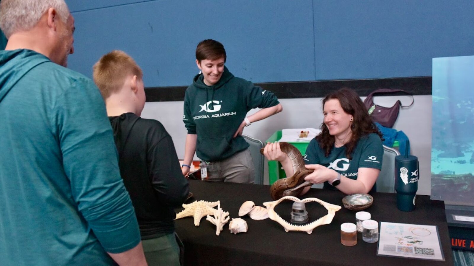 Georgia Aquarium educators show a snake, shells, coral and a shark jaw to a homeschool student and parent at a hands-on discovery station during Tuesdays in the Field