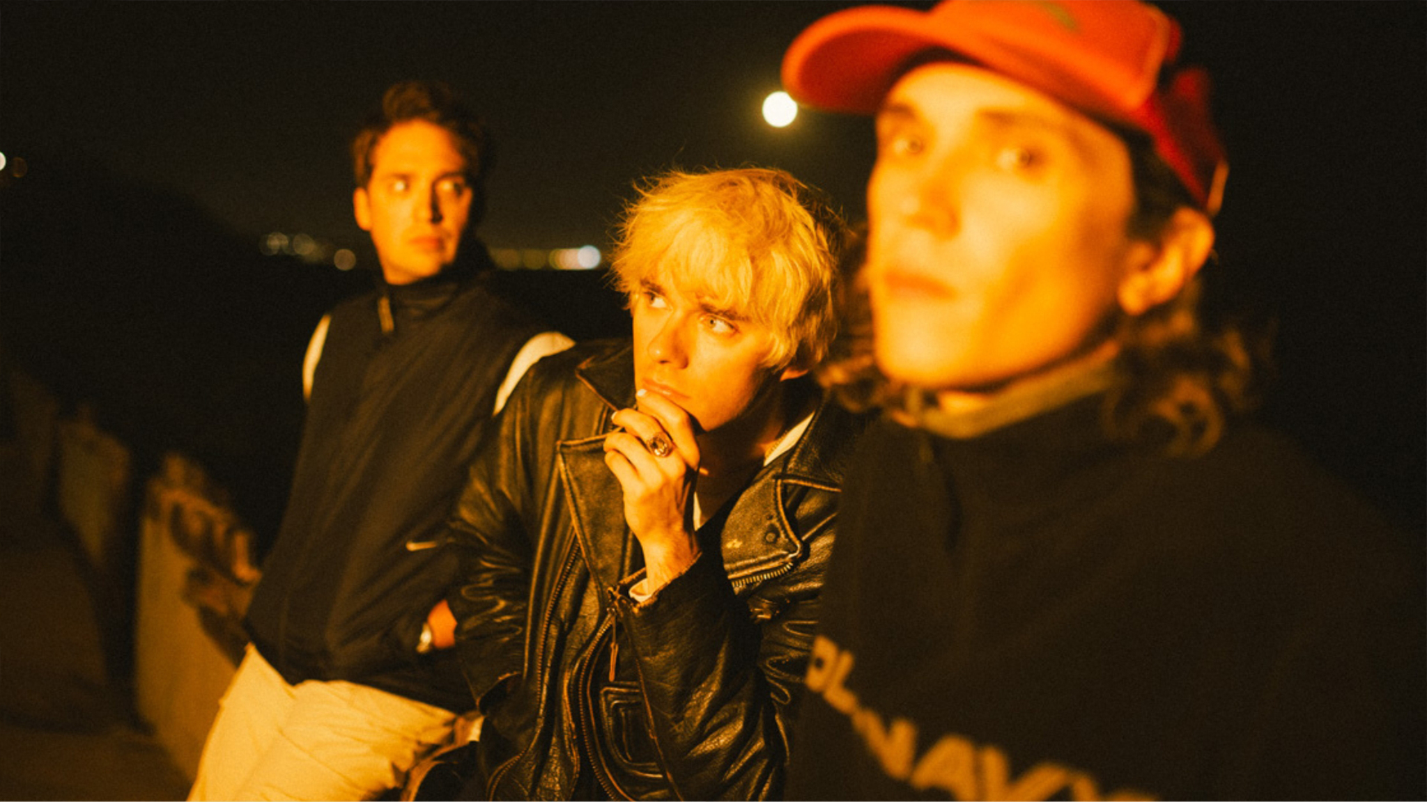 The three members of pop-punk band Waterparks posed together in brightly colored stage clothing.