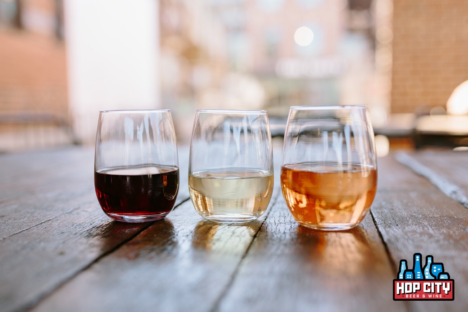 Three stemless glasses of red, white, and rose wine on a weathered wooden table at Hop City in Krog Street Market